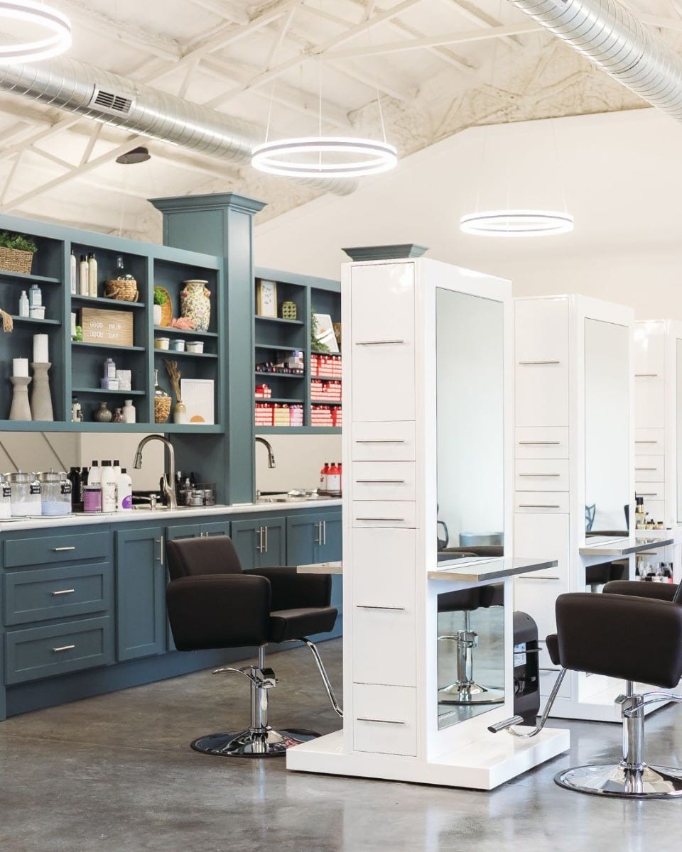 tall double-sided salon stations with full-length mirrors and built-in storage at use in a modern hair salon