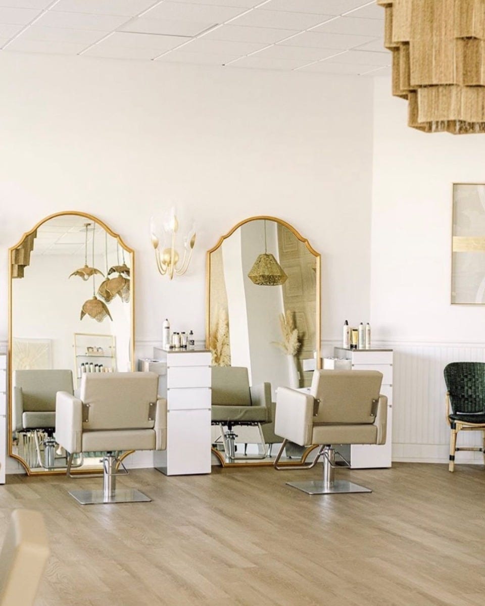14-inch wide modern minimalist pedestal style salon stations and large gilt-edged mirrors in small hair salon