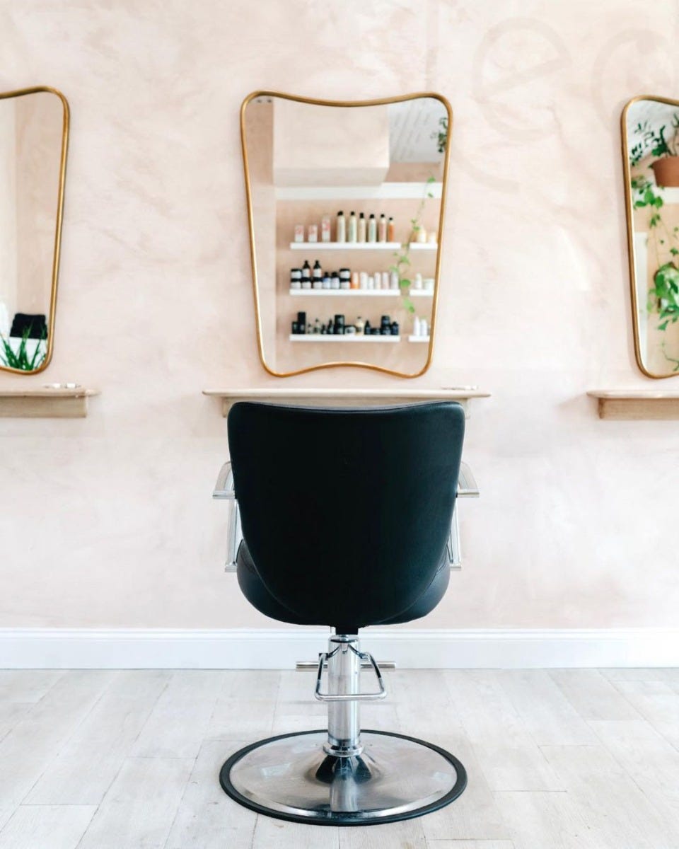 hair salon styling station with curved mirror, wall shelf and black styling chair