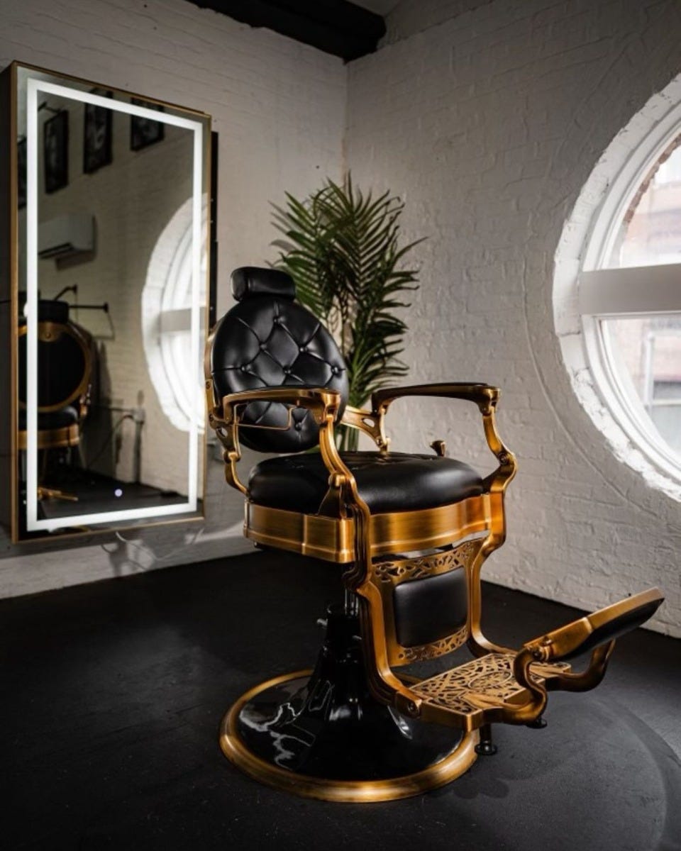 vintage style barber chair with gold frame and tufted black cushion in a luxury barber shop setting