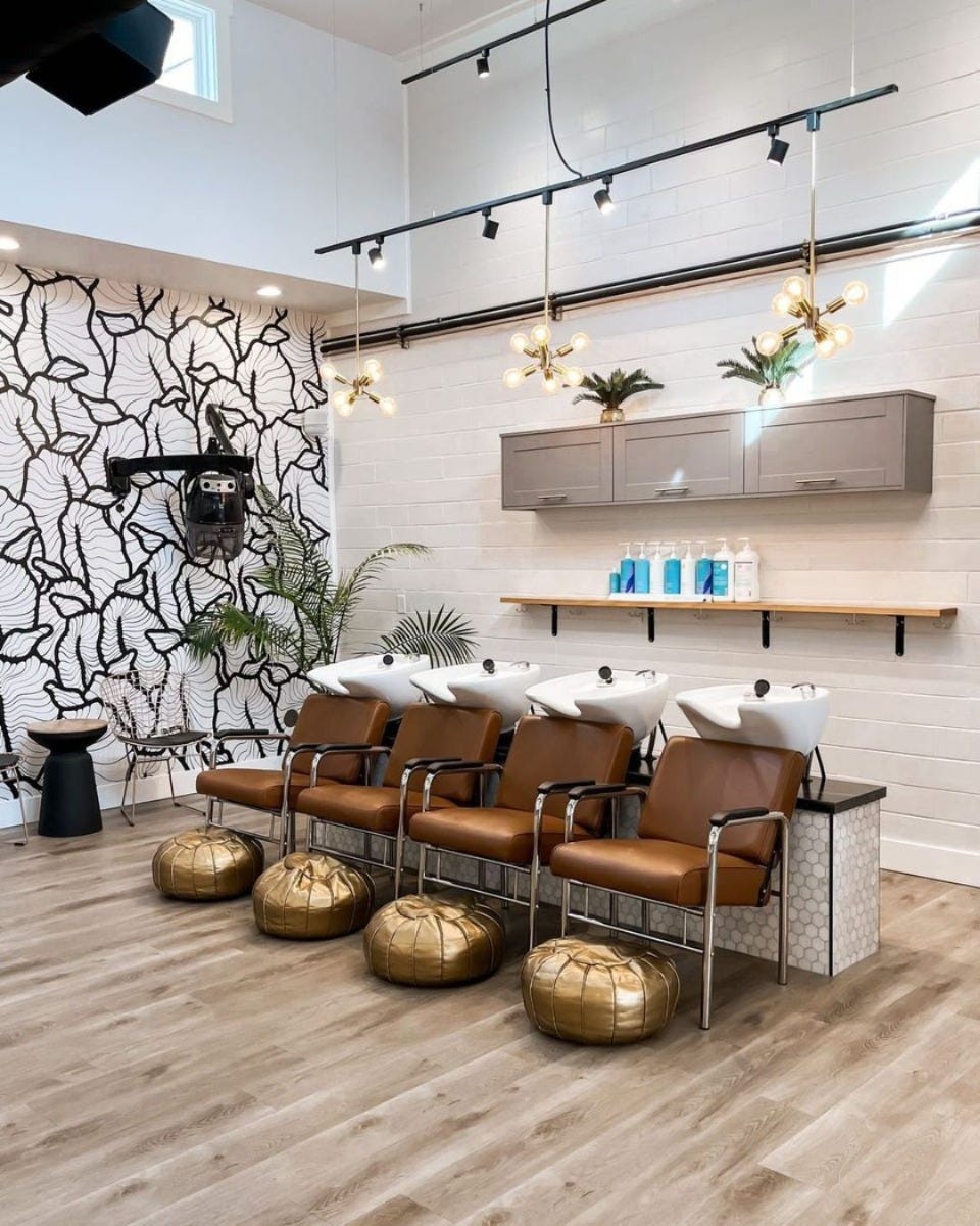 four shampoo stations with white sinks and brown shampoo chairs in an upscale hair salon