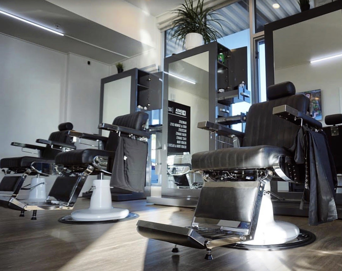 modern barber shop interior with black barber chairs and stainless steel barber stations with mirrors