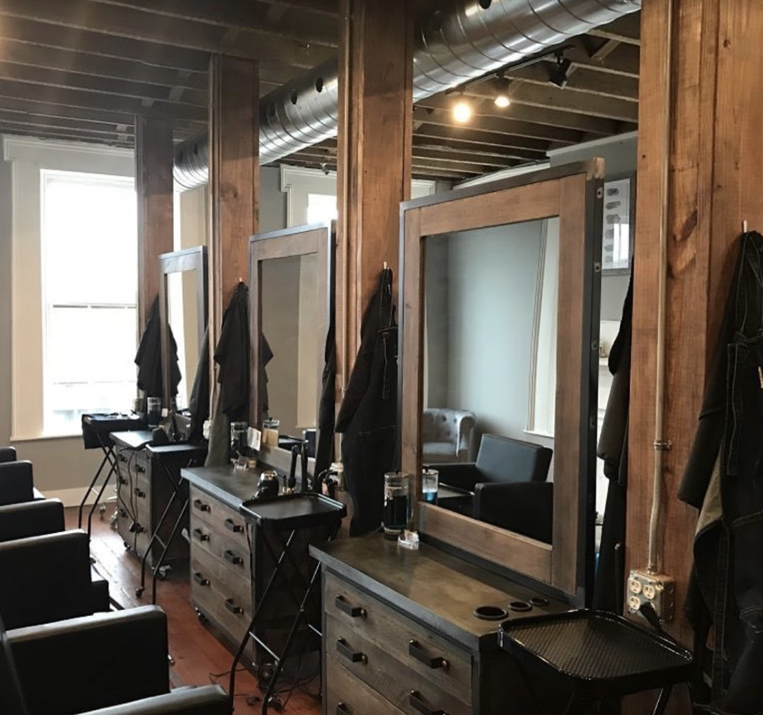 simple barber shop interior design with wood styling stations and black barber carts